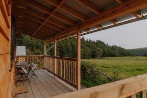 Una terraza de madera con una mesa y sillas. en Woolly Wood Cabins - Bryn, en Llandrindod Wells