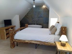 een slaapkamer met een houten bed en een bad bij Gîtes de l'Orée du Bois in Boussières