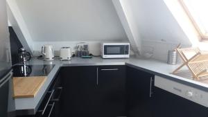 a kitchen with black cabinets and a white microwave at T2 à 9 mins du château 4pers in Le Chesnay +8 photos