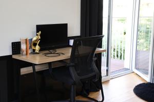 a desk with a computer monitor and a chair at Vienna's Modern Black Beauty - Couples & Family-Friendly apartment in Vienna