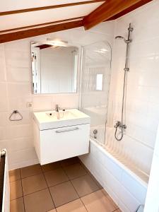ein weißes Bad mit einem Waschbecken und einer Dusche in der Unterkunft Zeepark Haerendycke in Wenduine
