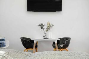 einen weißen Tisch mit Stühlen und einen TV an der Wand in der Unterkunft Summer Holiday Apartment At Beautiful Solgaarden in Svaneke