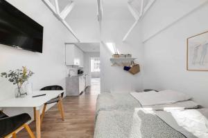 a white room with a bed and a table and a kitchen at Summer Holiday Apartment At Beautiful Solgaarden in Svaneke