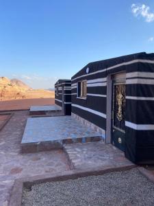 a black and white building with a door in the desert at Wadi Rum Nabatean Camp in Wadi Rum