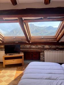 1 dormitorio con 2 camas, TV y ventana en Casa Rural Basiver - Suite Basiver en Armaño