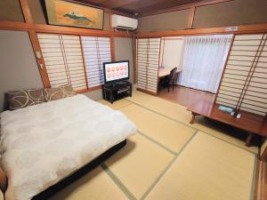 1 dormitorio con 1 cama y TV de pantalla plana en season guest house, en Tokio