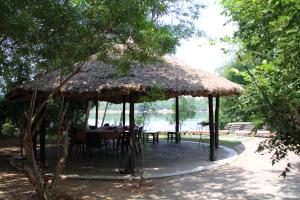een tafel en stoelen onder een rieten paraplu bij Panna Tiger Resort- Riverside Property in Rājgarh