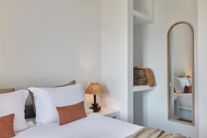 ein Schlafzimmer mit einem weißen Bett und einem Spiegel in der Unterkunft Iliana Olive Branch in Adamas
