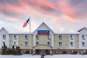 Um edifício com uma bandeira americana à frente. em Candlewood Suites South Bend Airport, an IHG Hotel em South Bend