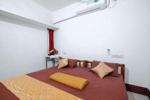 ein Schlafzimmer mit einem Bett mit gelbem Kissen darauf in der Unterkunft Manora Residency in Puducherry