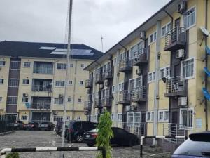 a large apartment building with cars parked in a parking lot at Kemzie's Apartments in Port Harcourt