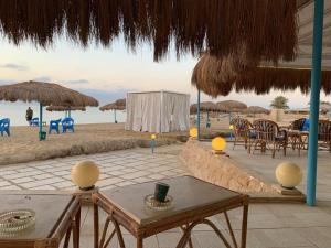 una spiaggia con tavoli, sedie e ombrelloni di شاليه فندقي ڤيو البحر Ain sokhna-families& married only a Ain Sokhna