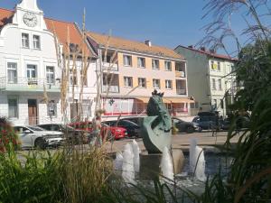 a statue in front of a building with a clock tower at Mikołajki Apartamenty Rynek in Mikołajki