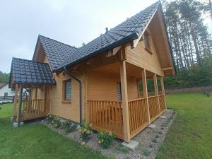 a small wooden cabin with a gambrel roof at Kaszubski dom pod lasem in Studzienice