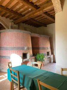 モンテリッジョーニにあるOstello Contessa Ava dei Lambardiのレンガ造りのオーブン付きの客室で、テーブルと椅子が備わります。