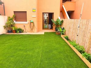 un patio con césped verde frente a una casa en Espacioso apartamento con preciosos jardines y BBQ, en Isla Plana
