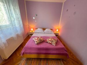 a bedroom with a purple bed with two pillows at Apartmani Ružić in Jadranovo