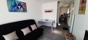 ein Wohnzimmer mit einem schwarzen Sofa und einem Tisch in der Unterkunft Jolie maisonnette à proximité de toutes commodités in Saintes-Maries-de-la-Mer