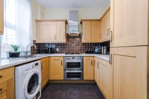 a kitchen with wooden cabinets and a washer and dryer at Stunning Spacious 2BR House in East Ardsley 