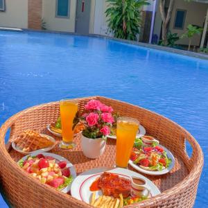 uma mesa com comida e bebidas num cesto ao lado de uma piscina em DINASTY STYLE HOTEL SOLO em Bonorejo