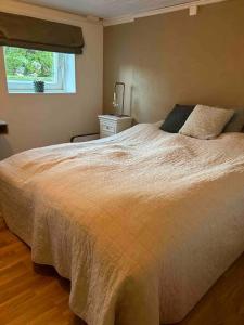 a bedroom with a large white bed with a window at Basement apartment in Sandefjord