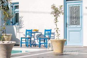 a patio with blue chairs and a table and a door at Jasmine Suites Poolhouse Rhodos in Koskinou