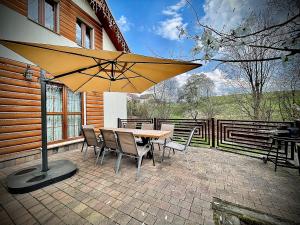 eine Terrasse mit einem Tisch, Stühlen und einem Sonnenschirm in der Unterkunft Domki Istebna 1544 in Istebna