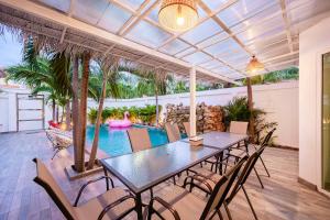 un patio con mesa, sillas y piscina en Majestic Residence Pool Villa 4 Bedrooms Private Beach en Pattaya South