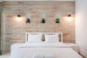 a bedroom with a white bed and a brick wall at Majestic Residence Pool Villa 4 Bedrooms Private Beach in Pattaya South