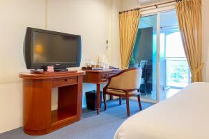 a bedroom with a desk with a television and a bed at Rim Tara Residence Patan in Chiang Mai