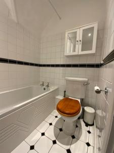 a bathroom with a toilet with a wooden toilet seat at Ipsley Lodge Apartment Surrey Hills in Farnham