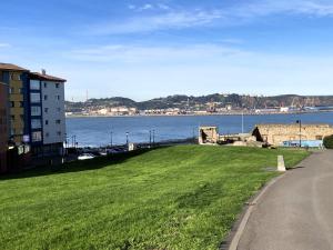 un champ herbeux à côté d’une masse d’eau dans l'établissement Apartamento El Espigón (Cimadevilla), à Gijón