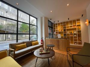 a living room with a couch and a table at Parici Hôtel Boulogne Billancourt in Boulogne-Billancourt