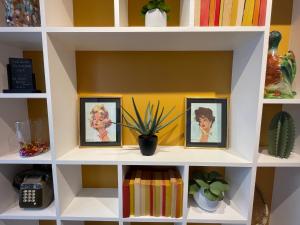 a white book shelf with three pictures and a plant at Parici Hôtel Boulogne Billancourt in Boulogne-Billancourt