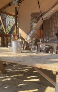 a wooden picnic table with wine glasses on it at Lodges & Nature - 47 in Avignon