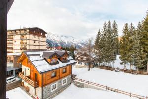 une maison dans la neige avec des montagnes en arrière-plan dans l'établissement Appartamento sulla piazzetta centrale, à Sauze dʼOulx