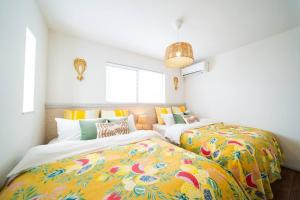dwa łóżka z kolorowymi kocami w pokoju w obiekcie Sun flower w mieście Nanjo