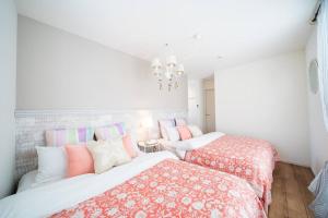 2 camas en una habitación de color blanco y rosa en Sun flower en Nanjo