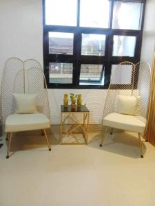 two chairs and a table in a room with windows at JP Suites & Residences in Tayabas