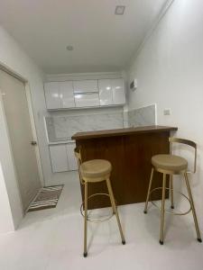 a kitchen with two bar stools and a counter at JP Suites & Residences in Tayabas
