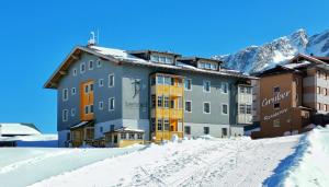 a large building in the snow with a mountain at Aparthotel Bernhof in Obertauern