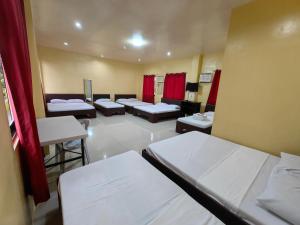 a room with four beds and a row of chairs at Lagnason's Place in Oslob