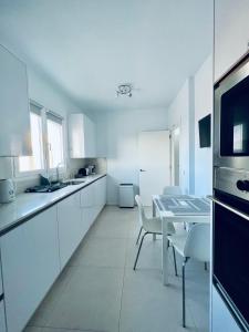 uma cozinha com armários brancos e uma mesa e cadeiras em Lovely Villa Sanmar, heated pool em Playa Blanca