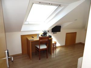 a attic room with a desk and a skylight at Pensión O Códice in Santiago de Compostela