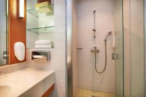 uma casa de banho com um chuveiro e um lavatório. em Holiday Inn Helsinki West - Ruoholahti, an IHG Hotel em Helsinque