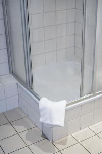 トリーアにあるHotel Constantinのバスルーム(シャワー、白いタオル付)
