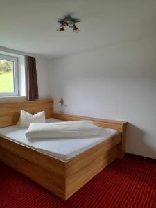 a bedroom with a wooden bed with a window at Hotel-Pension Wolfgang in Saalbach Hinterglemm