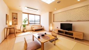 uma sala de estar com uma televisão e uma mesa em 宵待ちの宿　萩一輪 em Hagi