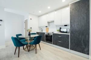 Inviting 2 Bedroom House in Dorking في دوركينغ: مطبخ مع دواليب بيضاء وطاولة وكراسي