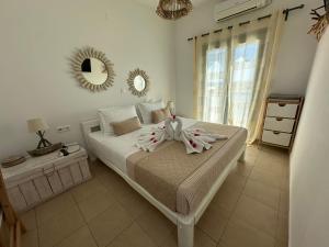 a bedroom with a white bed with a bow on it at Yialos Rooms in Piso Livadi